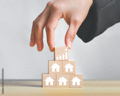Concept of real estate sales growth with icon on wooden cube stack,loan investment residential building house, real estate, property, mortgage.Arrow graph with house graph