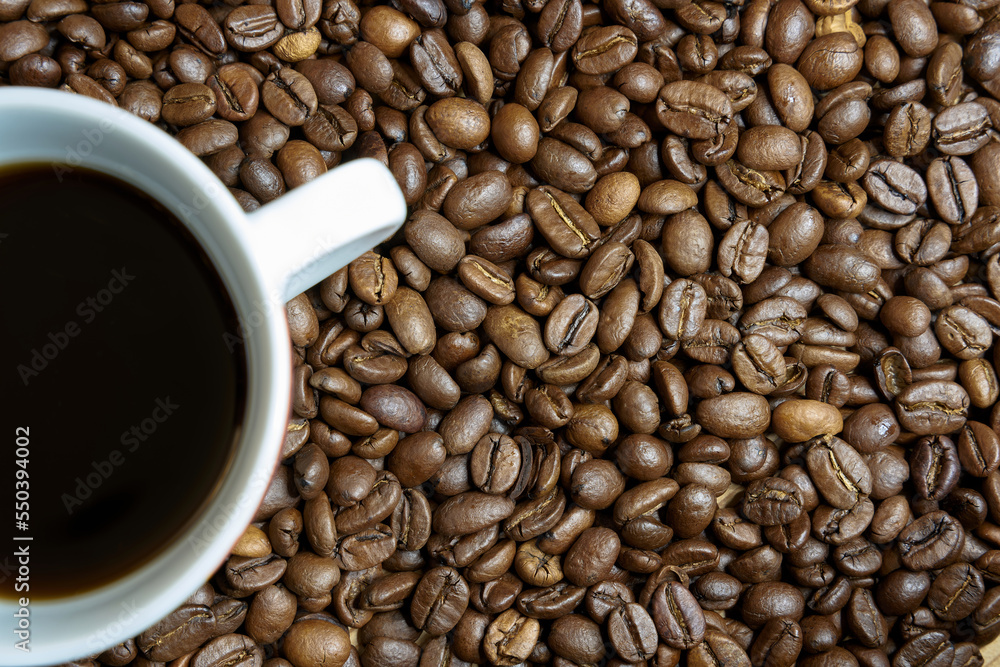 Fototapeta premium geröstete Kaffeebohnen und eine Tasse mit Kaffee auf einem Tisch