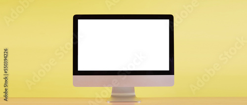 computer monitor with blank screen on wood table with yellow background.