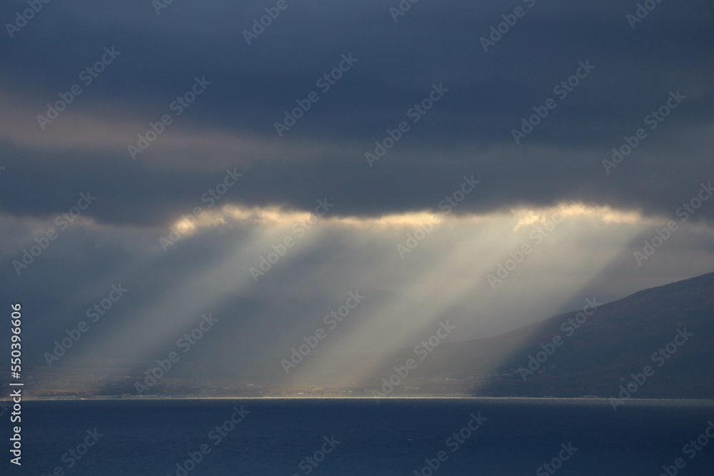the sun rays shine through the clouds on the sea surface the sun rays shine through the clouds on the sea surface