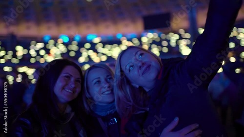 Girlfriends having fun at a concert take pictures of themselves on a mobilephone