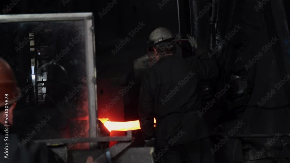 caucasian young strong blacksmith working with open fire in furnace. The blacksmith forging hot iron workshop.Red hot steel metal billets after molten steel casting. Continuous casting machine caucasian young strong blacksmith working with open fire in furnace. The blacksmith forging hot iron workshop.Red hot steel metal billets after molten steel casting. Continuous casting machine