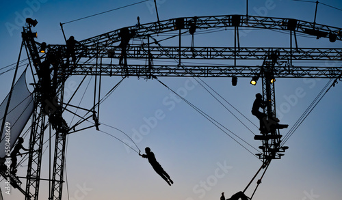 silhouettes of trapeze artists acrobats on the metal scaffolding at sunset