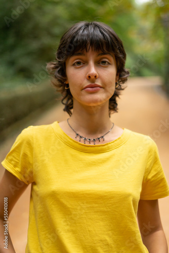 portrait of a young beautiful woman brunette looking at camera wearing a yellow t-shirt