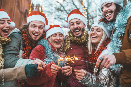 Group of friends holding sparklers celebrating Christmas day - Happy young people having party with fireworks at new year eve - Winter holidays concept