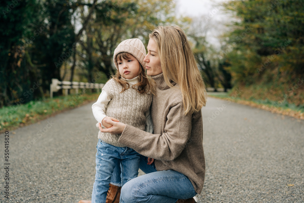 Mom and daughter walk in warm sweaters on an autumn day. Mom and daughter walk in warm sweaters on an autumn day.