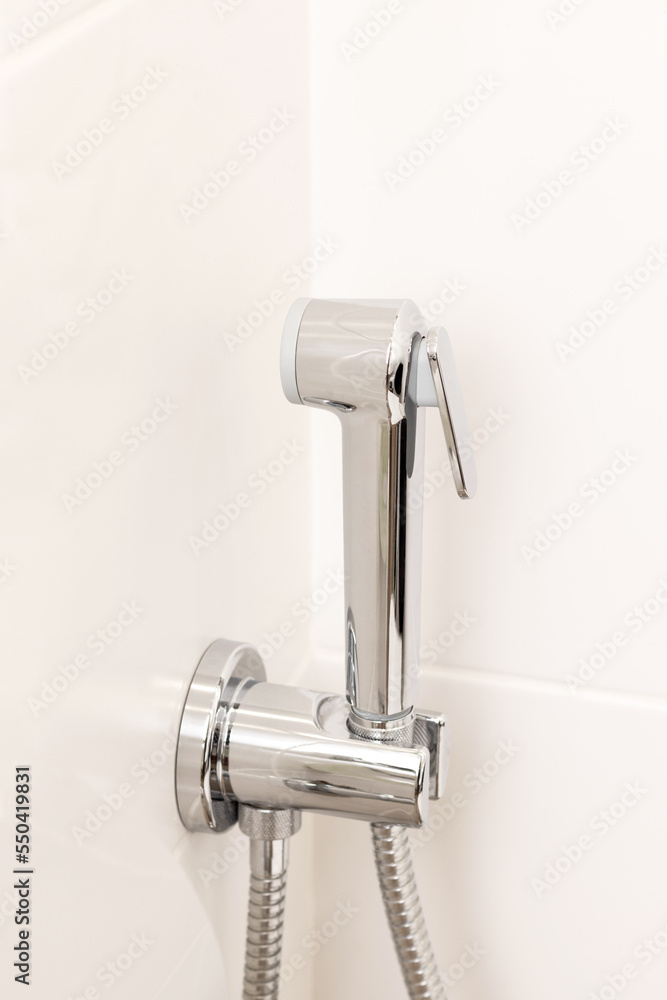 Hygienic shower on white tile wall. Details in bright modern bathroom Hygienic shower on white tile wall. Details in bright modern bathroom