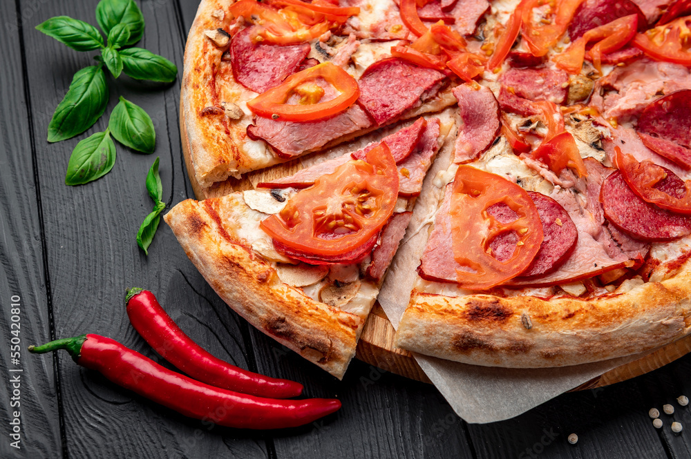 Italian pizza with ham, sausage, mushrooms, tomatoes and onions.