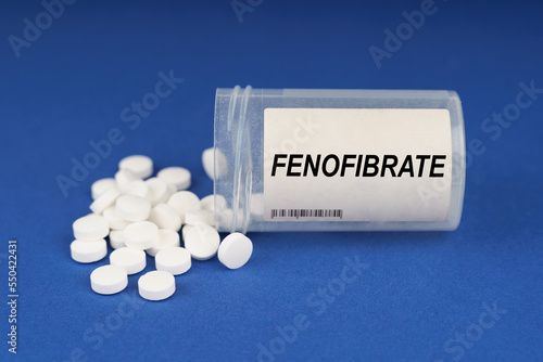 On a blue surface are pills and a dusty jar with the inscription - Fenofibrate photo
