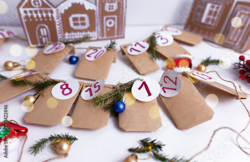 Hand made advent calendar. Preparation to christmas concept. Craft envelopes arranged on a white wall. Selective focus.