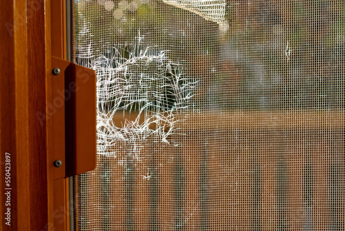 Close up image of torn window screen. Anti mosquito net damaged by birds and frequent usage. Protection against annoying insects. Repair needed