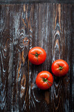 Appetizing composition in the kitchen of ripe red large tomatoes on a wooden dark textured table. Image for your creative design or decoration.