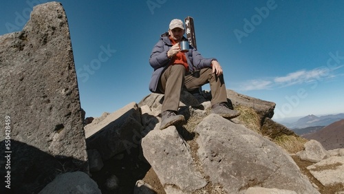 Man resting atop bick rocks, enjoy a cup of hot coffee on his break from hiking in Kuju, Japan photo