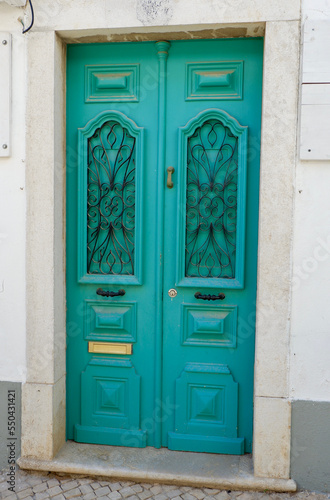 Vintage entrance door of vibrant blue colour and metallic ornamental details in Algarve, Portugal