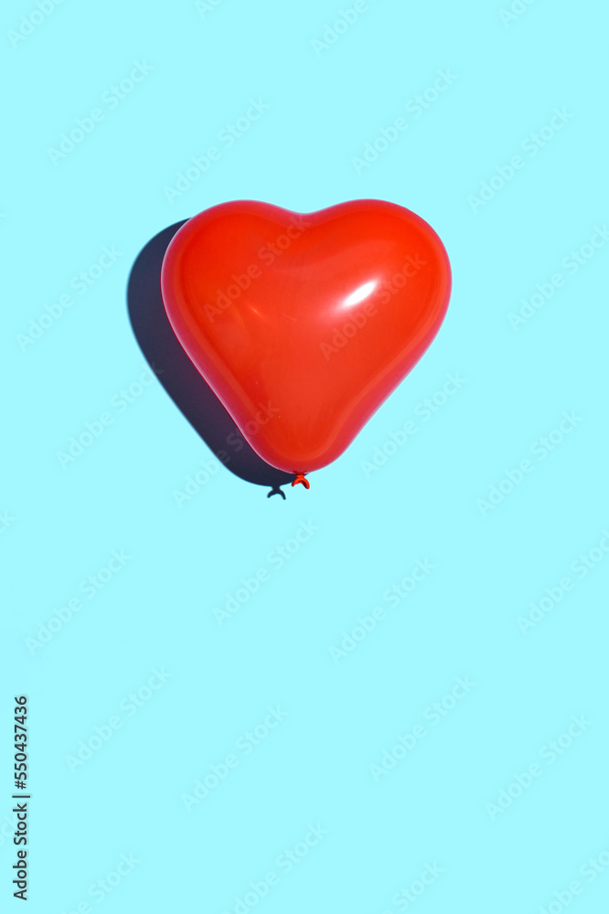 Red heart balloon against bright blue background. Minimal love concept. 