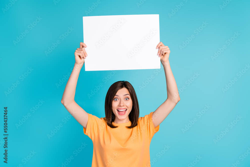 Photo of overjoyed cute lady wear stylish clothes hold paper sheet above head rejoice new shop open isolated on blue color background Photo of overjoyed cute lady wear stylish clothes hold paper sheet above head rejoice new shop open isolated on blue color background