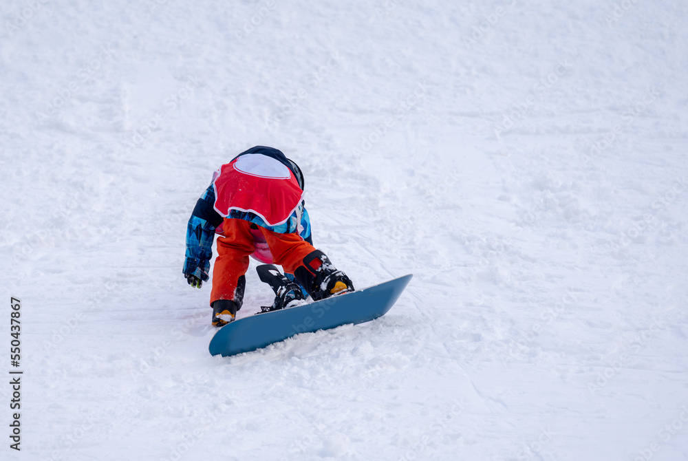 Person with snowboard on the snow. One Asian child is falling on the ground. Winter sport. Person with snowboard on the snow. One Asian child is falling on the ground. Winter sport.