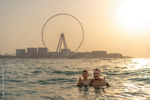 Canvas Print Dad and son swim in the sea with views of Dubai in the background