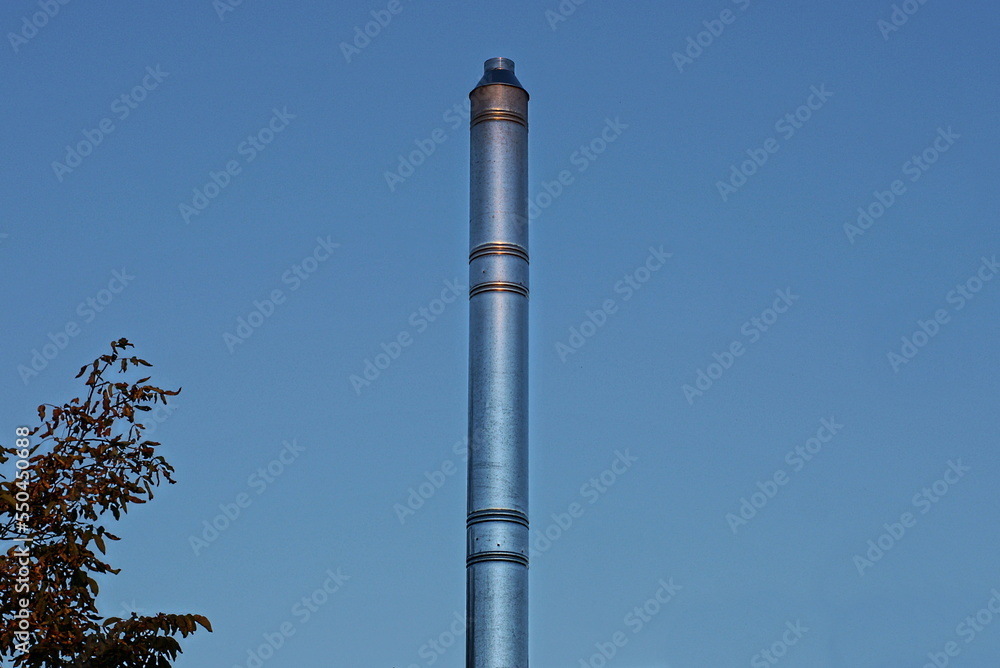 one long gray metal chimney pipe on the street against the blue sky