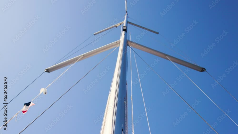 A view from below on the mast. Flag of France is on the sailing boat mast. Also we see cross-piece and shroud. A view from below on the mast. Flag of France is on the sailing boat mast. Also we see cross-piece and shroud.