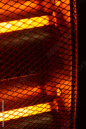 Close-up of two 500 watt electrical resistance heaters turned on. nice orange highlights in the heat reflectors. To save energy this winter, only one should be in operation.