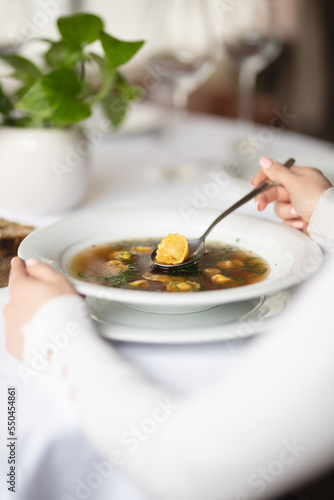 Soup with herbs on a light background. Bouillon. Restaurant serving. Waiter. Italian food.