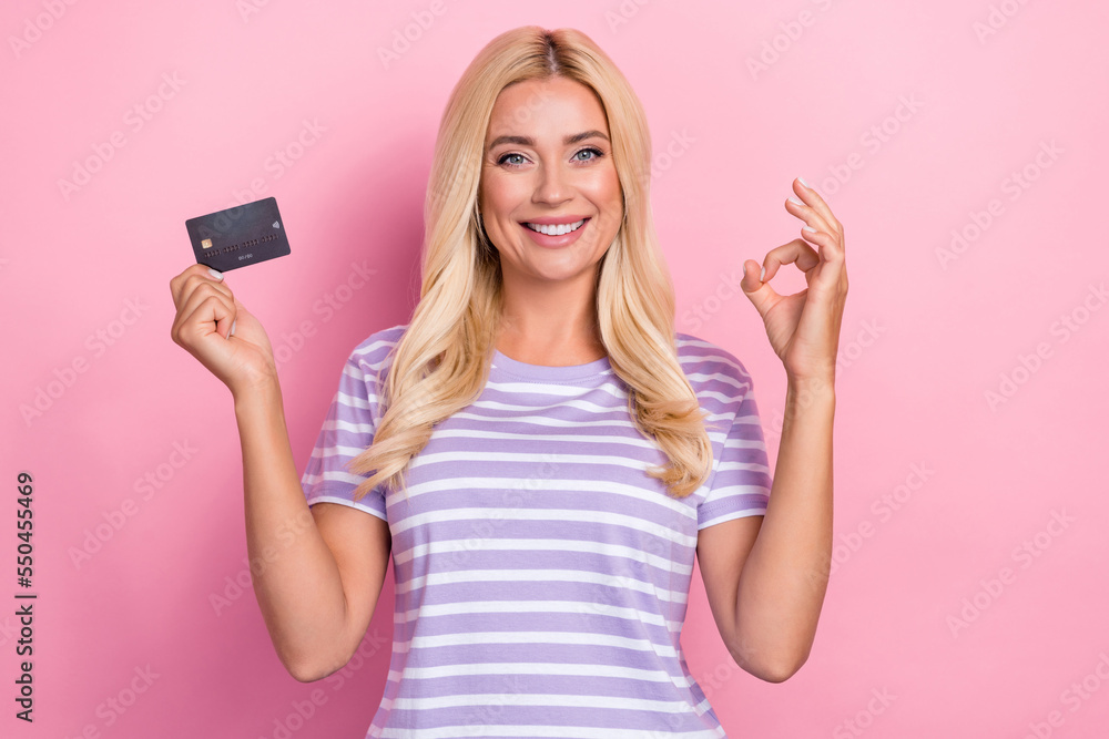 Photo of nice satisfied blonde hair lady wear striped purple t-shirt show okey sign recommend business card isolated on pink color background Photo of nice satisfied blonde hair lady wear striped purple t-shirt show okey sign recommend business card isolated on pink color background