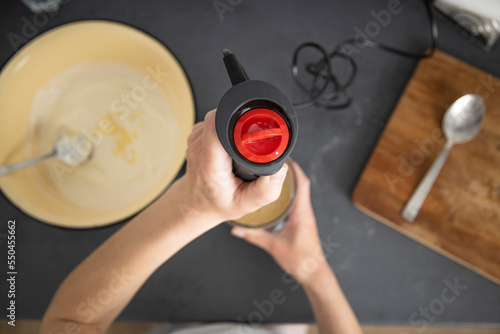 Woman whipping dough for baking with a mixer. Top view, flat lay