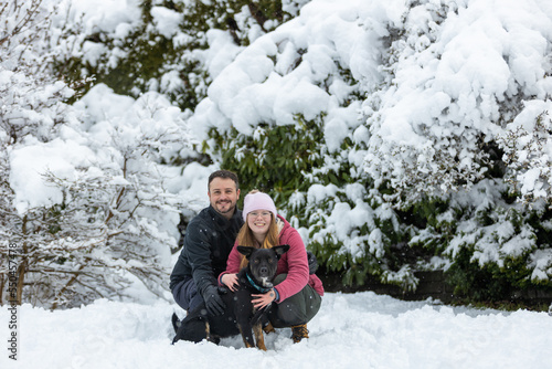 Young couple with dog outside in the snow