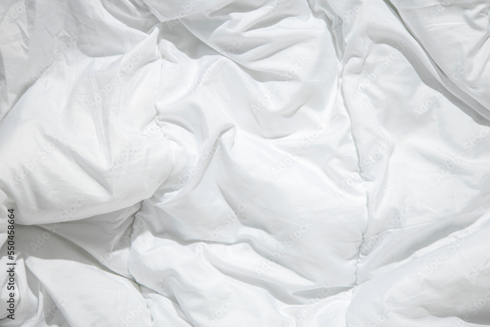 Wrinkled white blanket, an unmade bed. Top view, flat lay