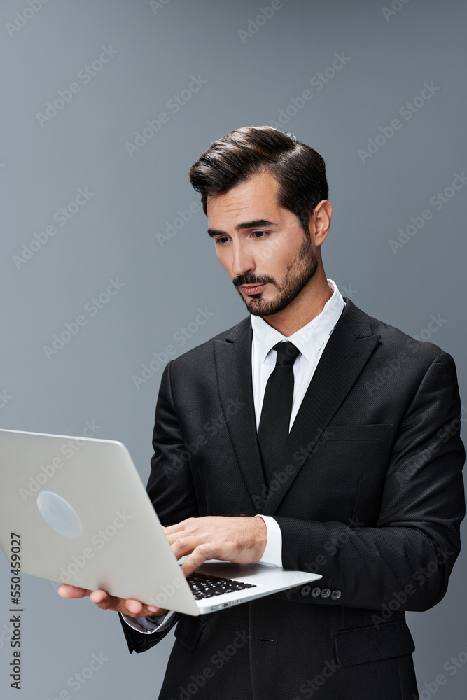 Man business looks into laptop and works thoughtfully online via internet in business suit video call business talks on gray background copy place Man business looks into laptop and works thoughtfully online via internet in business suit video call business talks on gray background copy place