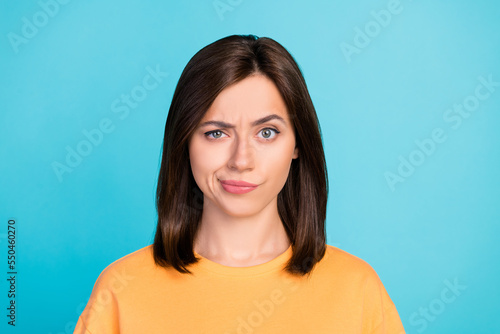 Portrait of gloomy funky serious cute girl with straight hairdo wear yellow t-shirt looks suspicious isolated on blue color background