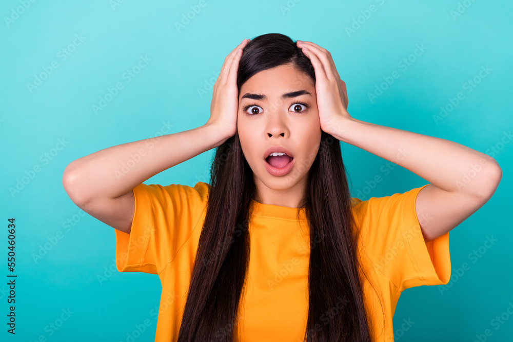 Photo of scared brunette millennial lady wear orange t-shirt isolated on teal color background Photo of scared brunette millennial lady wear orange t-shirt isolated on teal color background