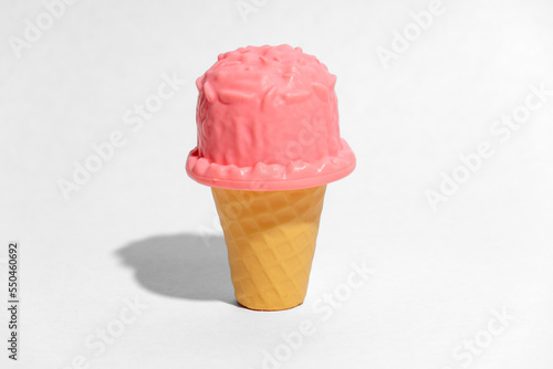 Toy pink ice cream in a cone on white background