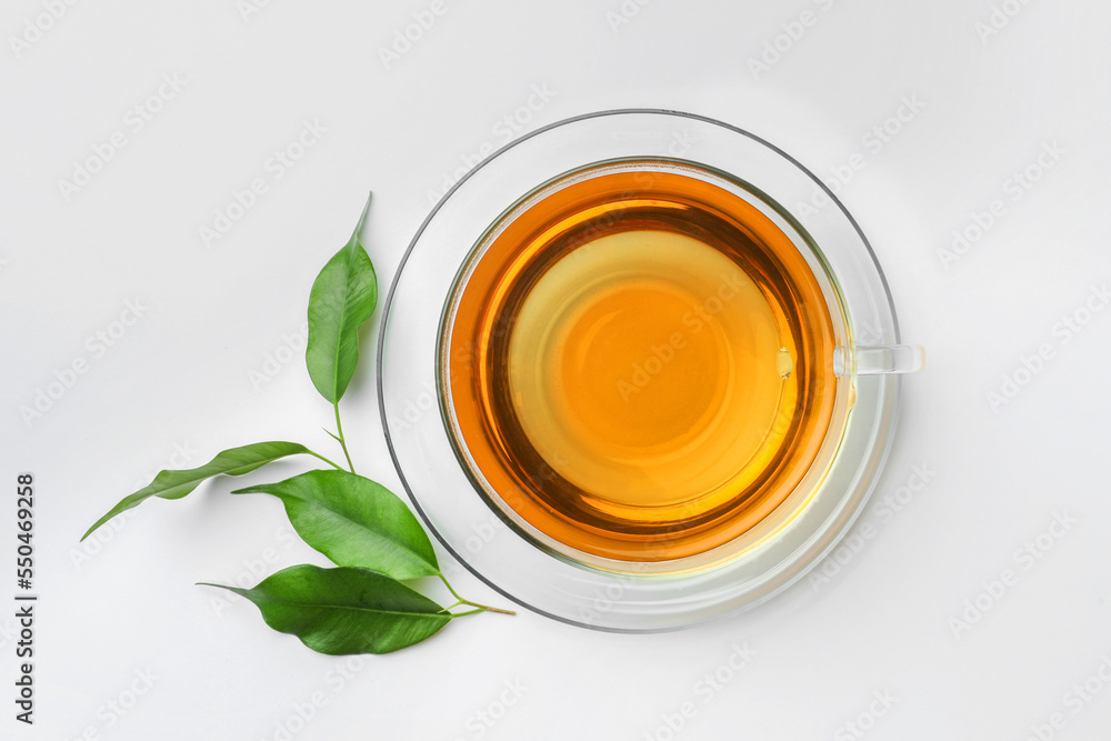 Fresh green tea in glass cup with saucer and leaves on white table, flat lay Fresh green tea in glass cup with saucer and leaves on white table, flat lay