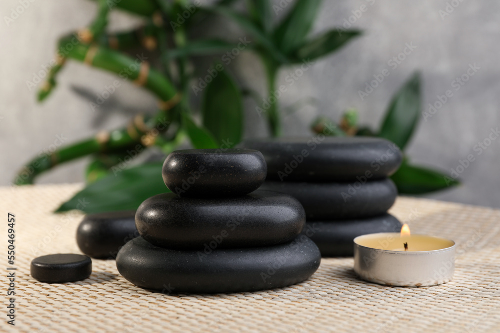Stacked spa stones, bamboo and candle on wicker mat Stacked spa stones, bamboo and candle on wicker mat