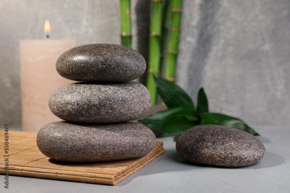 Spa stones, bamboo and candle on light grey table, space for text Spa stones, bamboo and candle on light grey table, space for text