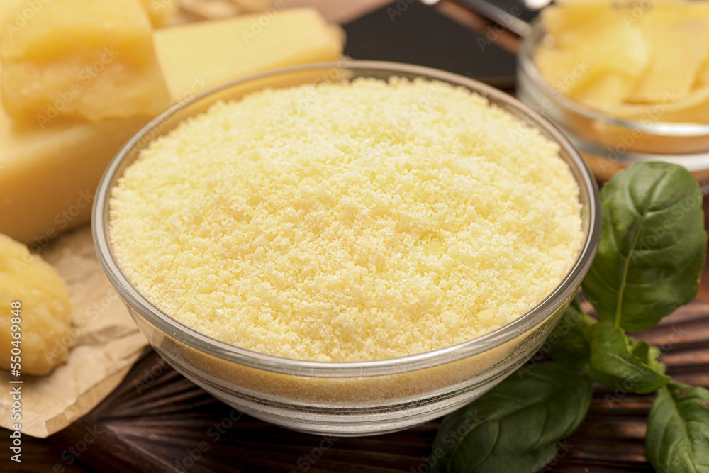 Delicious grated parmesan cheese in bowl on wooden table, closeup Delicious grated parmesan cheese in bowl on wooden table, closeup