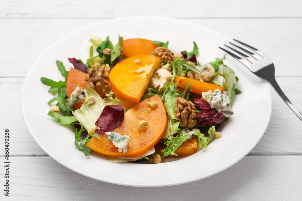 Delicious persimmon salad and fork on white wooden table, closeup Delicious persimmon salad and fork on white wooden table, closeup