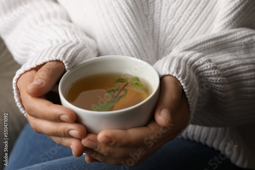 Woman drinking tasty herbal tea, closeup view