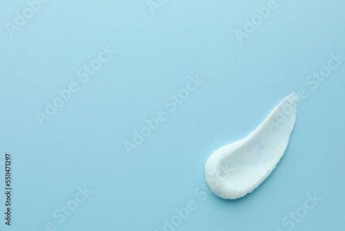 Sample of face scrub on light blue background, top view. Space for text