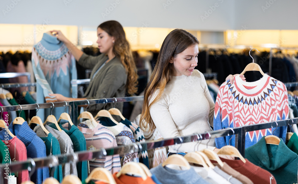 Young woman looking for casual sweater for cold days in showroom, having shopping day, find something on sale