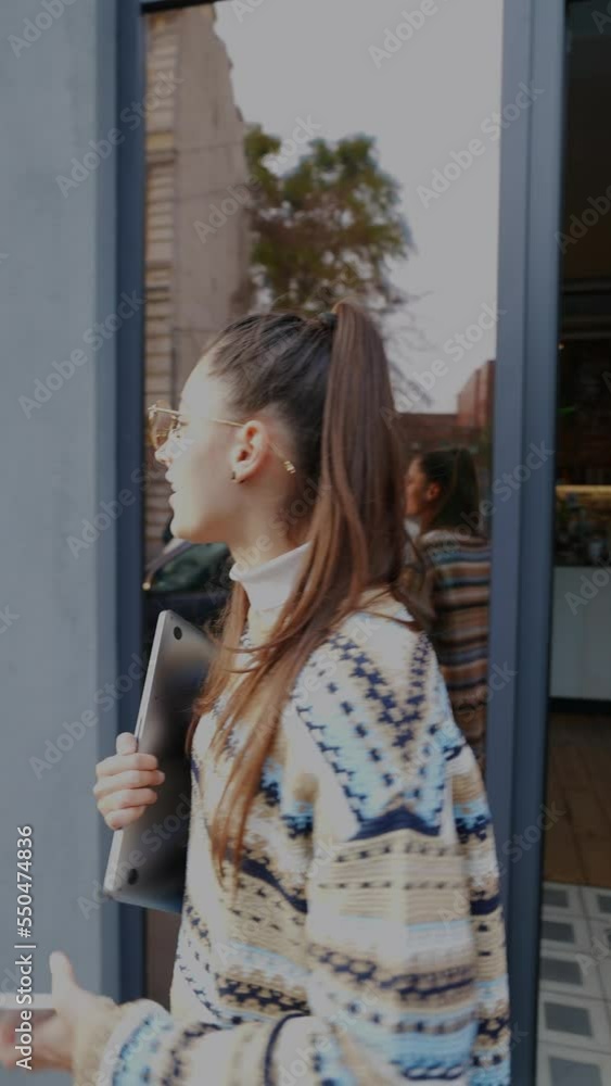 Young woman is talking on the phone while leaving the cafe Young woman is talking on the phone while leaving the cafe