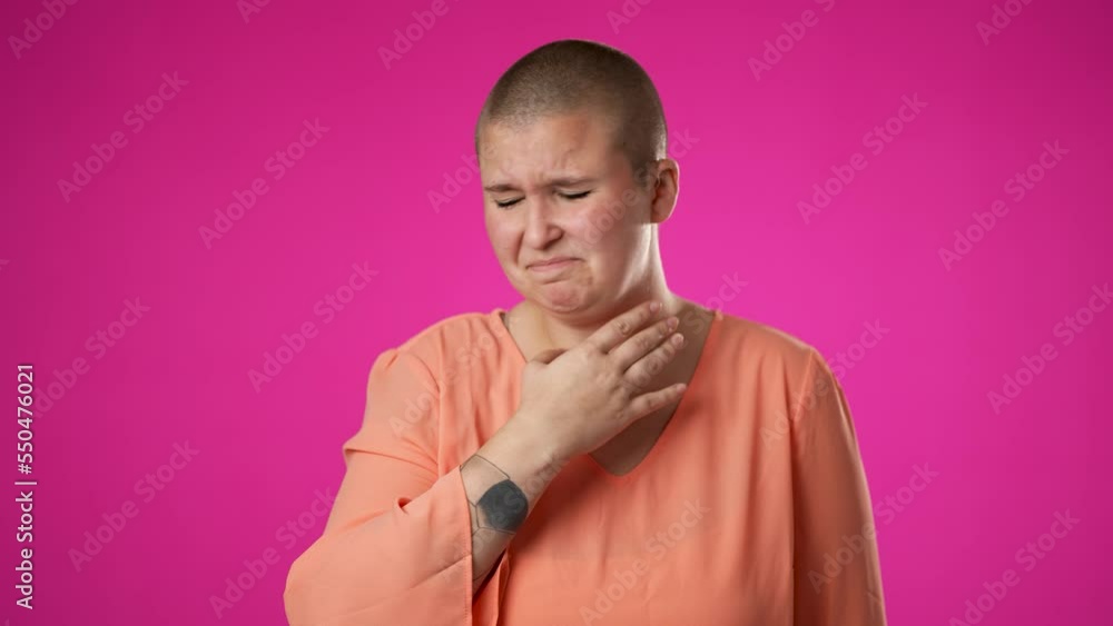 Portrait of gender fluid non binary young hipster woman 20s coughs into hand isolated on pink background studio. Healthy ill sick feel bad disease cold season Epidemic pandemic flu virus concept Portrait of gender fluid non binary young hipster woman 20s coughs into hand isolated on pink background studio. Healthy ill sick feel bad disease cold season Epidemic pandemic flu virus concept