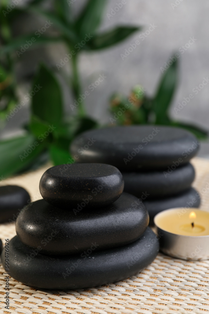 Obraz premium Stacked spa stones, bamboo and candle on wicker mat