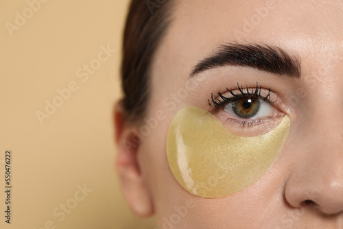 Canvas Print Beautiful woman with under eye patch on beige background, closeup