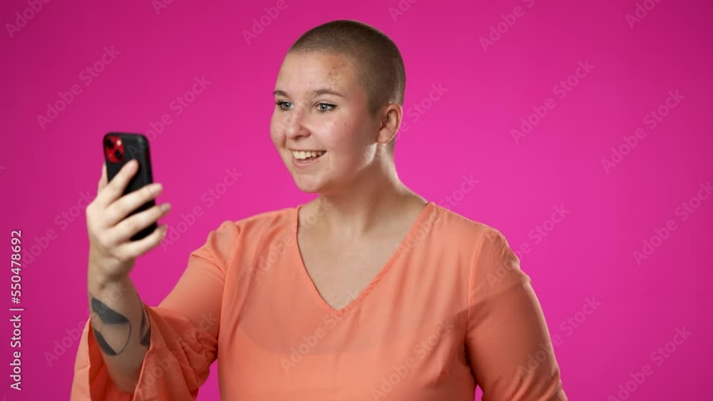 Portrait of happy smiling gender fluid non binary young woman 20s using speaking talking on mobile cell phone conducting pleasant conversation isolated on pink background studio. Portrait of happy smiling gender fluid non binary young woman 20s using speaking talking on mobile cell phone conducting pleasant conversation isolated on pink background studio.
