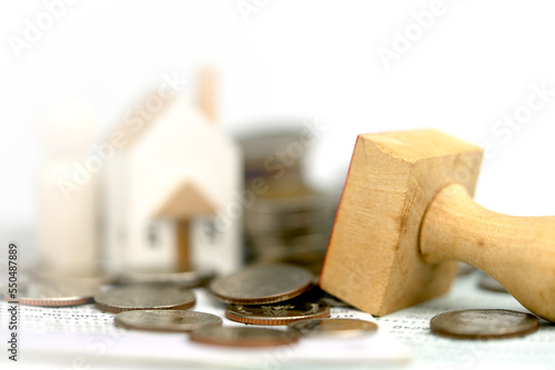 Approved mortgage loan agreement contract to new client. Wooden house shaped and stack of coins close-up. Business and finance concep.