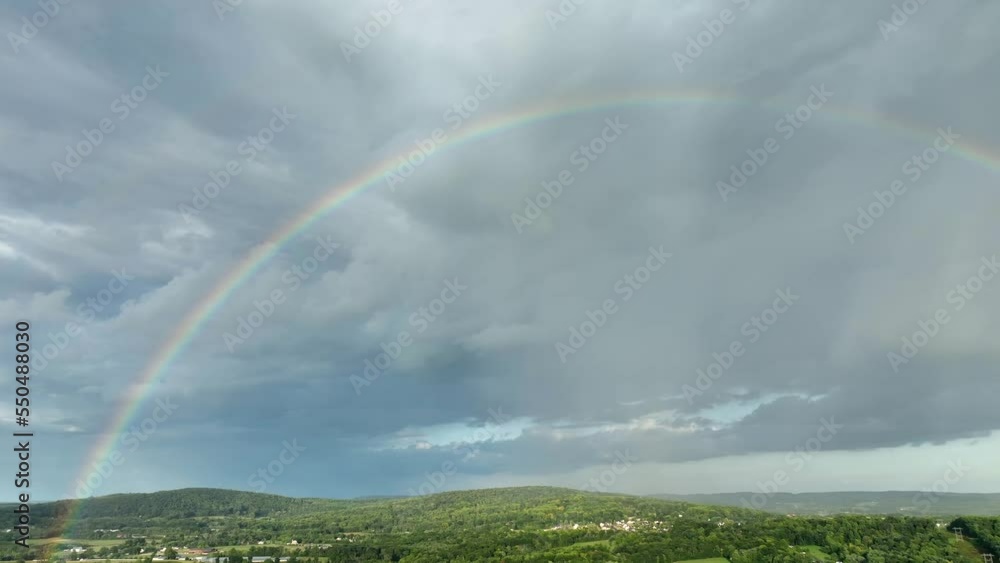 A right panning aerial view of a rainbow after a thunderstorm over the beautiful green countryside. A right panning aerial view of a rainbow after a thunderstorm over the beautiful green countryside.
