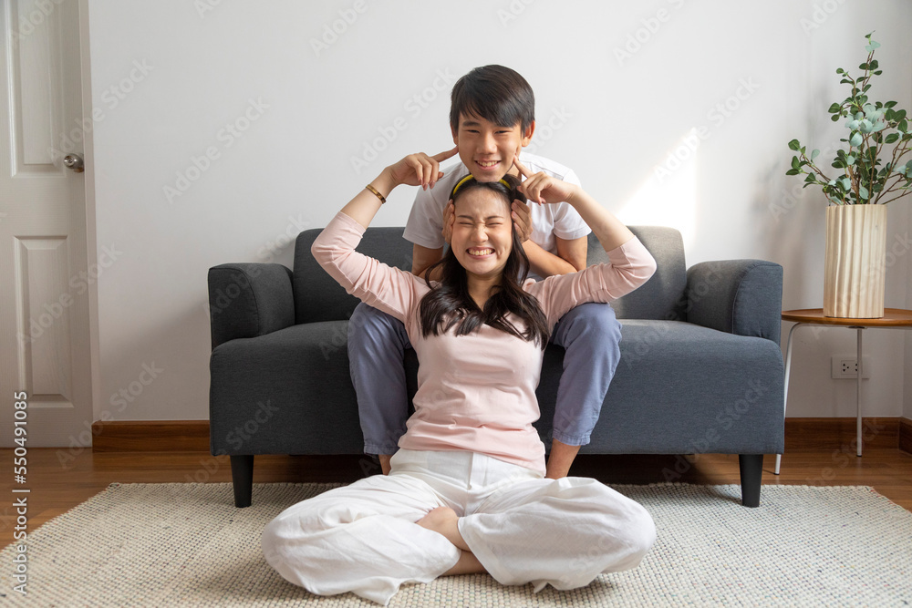 Asian brother and sister hugging with care and love sit on sofa at home. Asian brother and sister hugging with care and love sit on sofa at home.